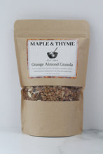 Load image into Gallery viewer, A standing pouch packaging of Maple &amp; Thyme Orange Almond Granola. The package is brown with a clear window showing the granola inside.
