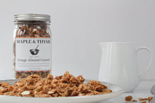 Load image into Gallery viewer, jar of orang almond granola with a plate of orange almond granola and a white pitcher. 
